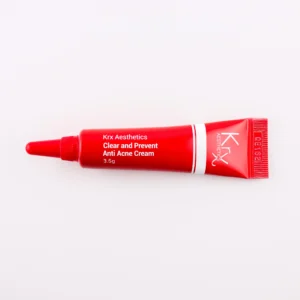 Das Bild zeigt eine tiefrote Tube mit einer spitzen Dosierspitze, die auf einem beigen Hintergrund liegt. Das Produkt gehört zur KRX Aesthetics-Reihe und heißt „Clear and Prevent Anti Acne Cream“. Die Tube ist rot mit weißem Schriftzug und einer dünnen weißen Linie. Die Füllmenge beträgt 3,5 g. Die Beleuchtung ist sanft und gleichmäßig.