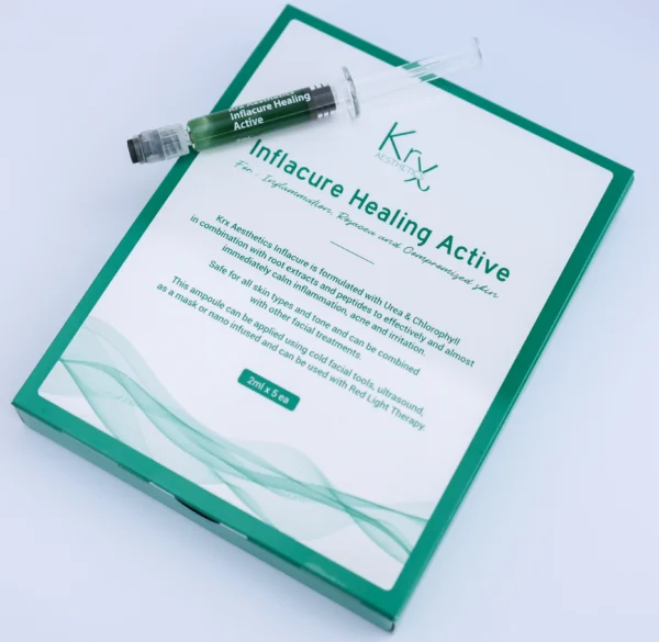Das Bild zeigt eine Produktverpackung von KrX Aesthetics mit dem Namen Inflacure Healing Active. Die rechteckige Verpackung ist überwiegend weiß mit grünen Akzenten und einem dezenten Wellenmuster. Im Zentrum steht der Produktname in grün: „Inflacure Healing Active – For Inflammation, Repair and Compromised Skin“. Auf der Verpackung befindet sich ein transparenter Kunststoffbehälter in Form einer Spritze (Ampulle) mit grünem Inhalt. Der Aufdruck auf der Ampulle lautet ebenfalls „Inflacure Healing Active“. Es handelt sich um eine beruhigende Wirkstoffampulle zur Hautregeneration, speziell entwickelt zur Behandlung von entzündlicher oder gereizter Haut. Am unteren Rand der Verpackung steht: „2 ml × 5 ea“, was auf fünf Ampullen mit je 2 ml Inhalt hinweist.