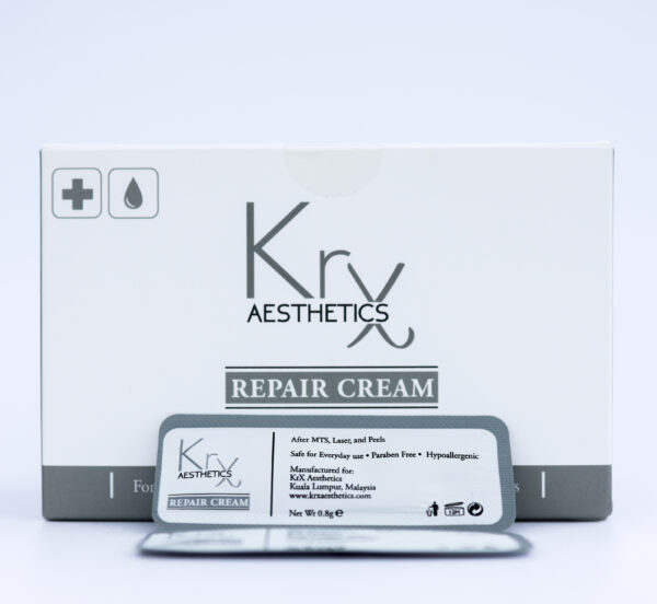 Das Bild zeigt eine Hand, die zwei kleine silberfarbene Sachets mit weißer Beschriftung in die Kamera hält. Es handelt sich um die “KrX Aesthetics Repair Cream”, eine Creme in Probiergröße, verpackt in Einzeldosen (Sachets). Die Verpackung ist schlicht und professionell gestaltet. Auf den Sachets steht, dass die Creme speziell für die Pflege nach Hautbehandlungen wie MTS (Microneedling), Laser oder Peels gedacht ist.
