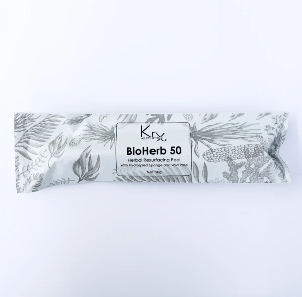 Auf dem Bild ist ein länglicher, flach verpackter Beutel des Produkts KrX Aesthetics BioHerb 50 zu sehen. Die Verpackung ist weiß mit einem feinen, pflanzlichen Muster in Grautönen – verschiedene Kräuter, Blätter und Naturmotive zieren das Design. In der Mitte befindet sich ein weißes Etikett mit schwarzem Aufdruck. Dort steht der Produktname: „BioHerb 50 – Herbal Resurfacing Peel“. Darunter ist vermerkt: „With Hydrolyzed Sponge and Wild Rose“. Die Nettofüllmenge beträgt 20g.