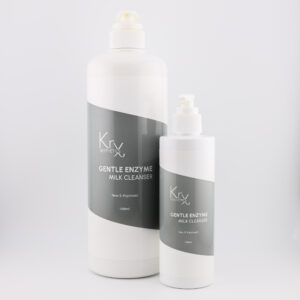 Das Bild zeigt zwei Pumpspender-Flaschen des Gentle Enzyme Milk Cleansers von KrX Aesthetics. • Links ist die größere Profiflasche mit 1000 ml, • rechts daneben die kleinere Variante mit 250 ml. Beide Verpackungen sind im gleichen Design gehalten: weißer Kunststoffkörper mit schräg verlaufendem, dunkelgrauen Etikett. Die weiße Schrift darauf trägt die Bezeichnung: KrX AESTHETICS GENTLE ENZYME MILK CLEANSER New & Improved Die Flaschen sind schlicht, modern und hygienisch gestaltet – perfekt für den professionellen Einsatz in Kabinen oder für die Heimpflege.