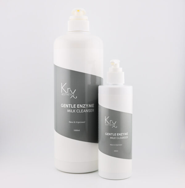 Das Bild zeigt zwei Pumpspender-Flaschen des Gentle Enzyme Milk Cleansers von KrX Aesthetics. • Links ist die größere Profiflasche mit 1000 ml, • rechts daneben die kleinere Variante mit 250 ml. Beide Verpackungen sind im gleichen Design gehalten: weißer Kunststoffkörper mit schräg verlaufendem, dunkelgrauen Etikett. Die weiße Schrift darauf trägt die Bezeichnung: KrX AESTHETICS GENTLE ENZYME MILK CLEANSER New & Improved Die Flaschen sind schlicht, modern und hygienisch gestaltet – perfekt für den professionellen Einsatz in Kabinen oder für die Heimpflege.