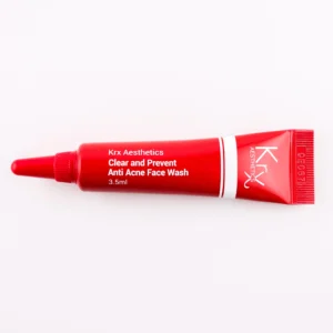 Hier ist eine weitere tiefrote Tube zu sehen, die zur KRX Aesthetics-Reihe gehört. Das Produkt trägt den Namen „Clear and Prevent Anti Acne Face Wash“. Die Tube hat ein Design mit weißer Schrift und einer dünnen weißen Linie und enthält 3,5 ml des Produkts. Das Produkt liegt auf einem beigen Hintergrund mit gleichmäßiger Beleuchtung.