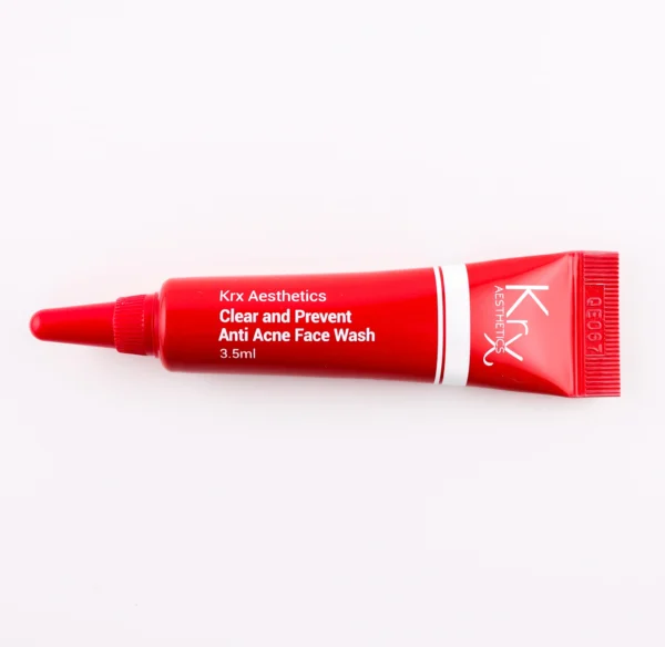 Hier ist eine weitere tiefrote Tube zu sehen, die zur KRX Aesthetics-Reihe gehört. Das Produkt trägt den Namen „Clear and Prevent Anti Acne Face Wash“. Die Tube hat ein Design mit weißer Schrift und einer dünnen weißen Linie und enthält 3,5 ml des Produkts. Das Produkt liegt auf einem beigen Hintergrund mit gleichmäßiger Beleuchtung.