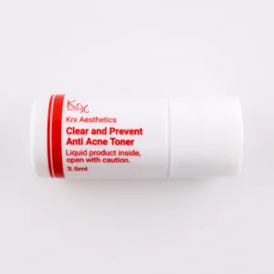 Das Bild zeigt einen kleinen, weißen Zylinderbehälter mit einem Drehverschluss, liegend auf einem beigen Hintergrund. Das Produkt gehört zur KRX Aesthetics-Reihe und trägt den Namen „Clear and Prevent Anti Acne Toner“. Der Behälter hat eine rote Beschriftung und enthält 3,5 ml Flüssigkeit. Zusätzlich steht auf dem Etikett: „Liquid product inside, open with caution.“ Die Beleuchtung ist weich und gleichmäßig.