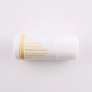 Dieses Bild zeigt einen weiteren kleinen, weißen Zylinderbehälter mit einer goldenen Beschriftung. Das Produkt gehört zur KRX Aesthetics-Reihe und heißt „All Day Glow Quenching Toner“. Es enthält 3,5 ml Flüssigkeit und trägt dieselbe Warnung wie die anderen Toner: „Liquid product inside, open with caution.“ Der Hintergrund ist beige, und die Beleuchtung ist gleichmäßig.