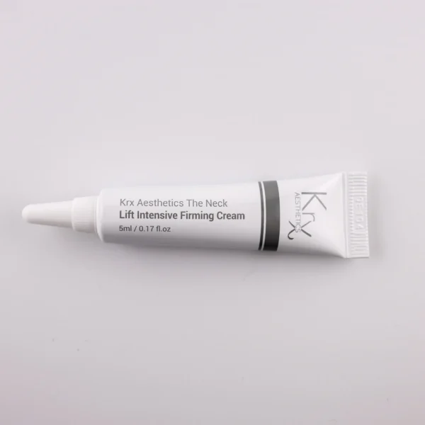 Das Bild zeigt eine kleine Tube mit einer spitzen Dosierspitze, liegend auf einem beigen Hintergrund. Das Produkt gehört zur Marke KRX Aesthetics und trägt die Bezeichnung „The Neck Lift Intensive Firming Cream“. Die Tube ist überwiegend weiß mit einem grauen und schwarzen Designelement an der Seite. Der Schriftzug lautet: „KRX Aesthetics The Neck Lift Intensive Firming Cream“, mit einer Füllmenge von 5 ml (0.17 FL.OZ.). Die Beleuchtung ist weich und gleichmäßig.