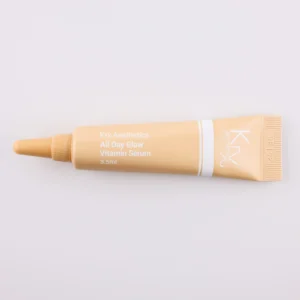 Dieses Bild zeigt eine beige Tube mit einer spitzen Dosierspitze auf einem beigen Hintergrund. Das Produkt stammt von KRX Aesthetics und heißt „All Day Glow Vitamin Serum“. Die Tube hat eine weiße Beschriftung mit einer dünnen weißen Linie und enthält 3,5 g. Die Beleuchtung ist sanft und gleichmäßig.